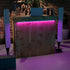 Wooden bar with pink LED lighting against a brick wall