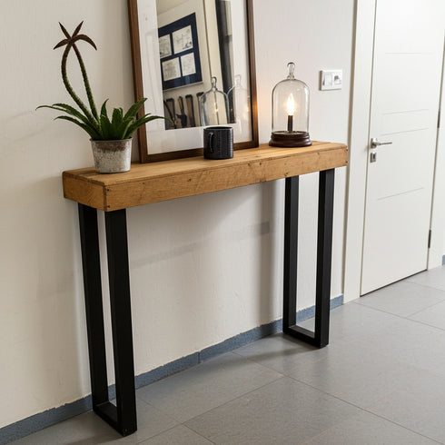 Wooden console table with black legs against a wall in a room.