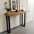 Wooden console table with black legs against a wall in a room.