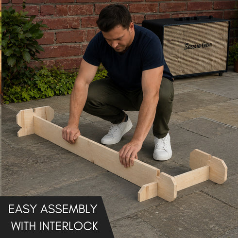 Man assembling a wooden garden bed with interlocking pieces on a patio.