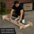 Man assembling a wooden garden bed with interlocking pieces on a patio.