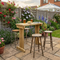 Outdoor patio area with wooden table, stools, and potted plants in a garden setting.