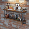 Wooden bar shelf with bottles, glasses, and a clock against a brick wall.