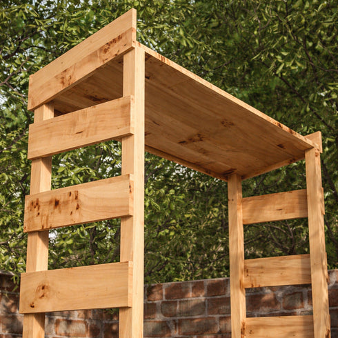 Wooden gardem bar with a roof and shelves against a green leafy background