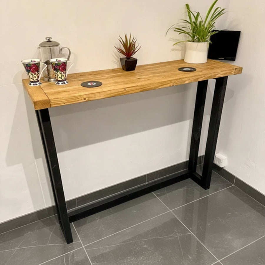 Wooden console table with black legs against a white wall