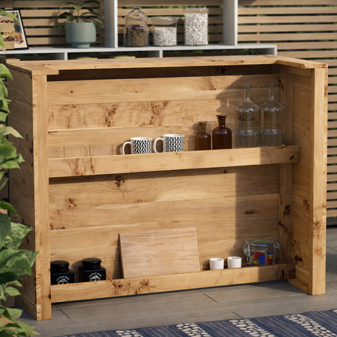 Wooden outdoor bar with various items on shelves against a neutral background