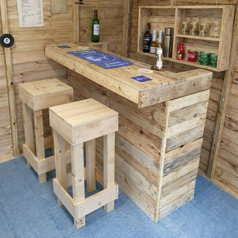 Wooden bar setup with stools and various bottles in a rustic setting.