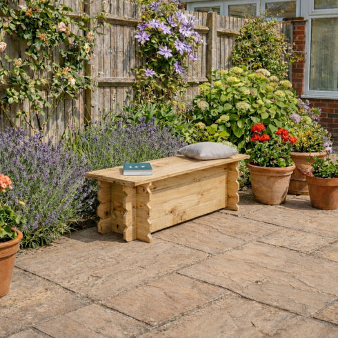 Wooden bench in a garden with potted plants and flowers on a stone patio.