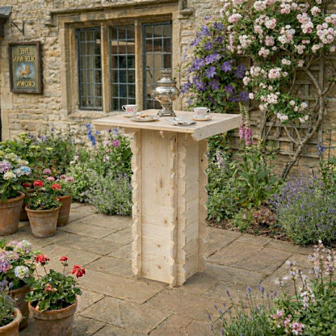 Wooden garden table with tea set surrounded by flowers and plants in a garden setting.